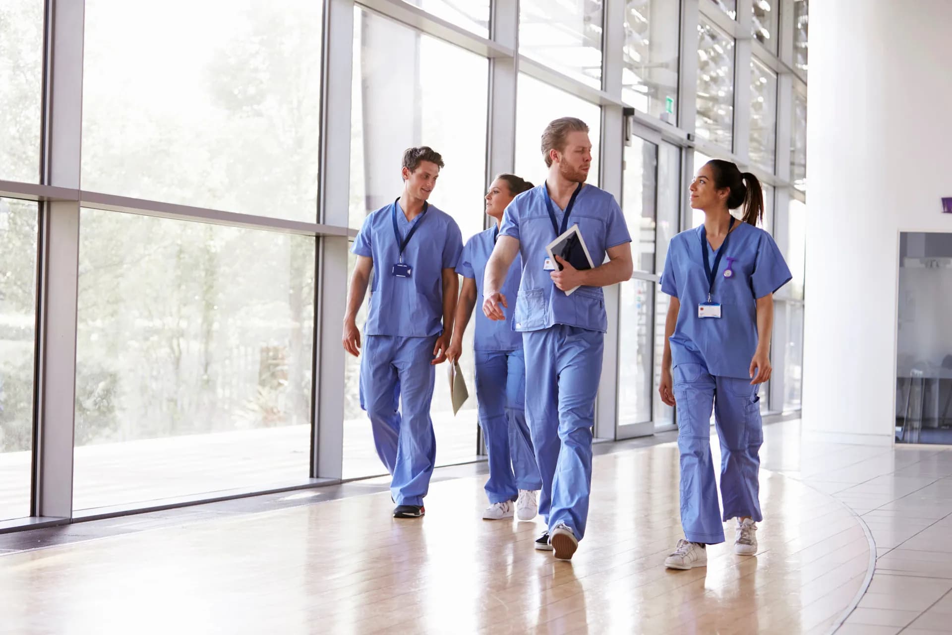 Internationale Pflegefachpersonen gehen gemeinsam durch eine moderne Klinik in Deutschland